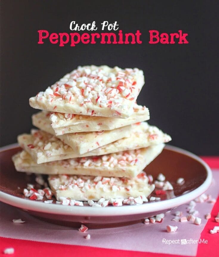 Crock Pot Peppermint Bark stacked on a plate with crushed peppermint candy, dark background, festive holiday dessert image from A Hundred Affections.
