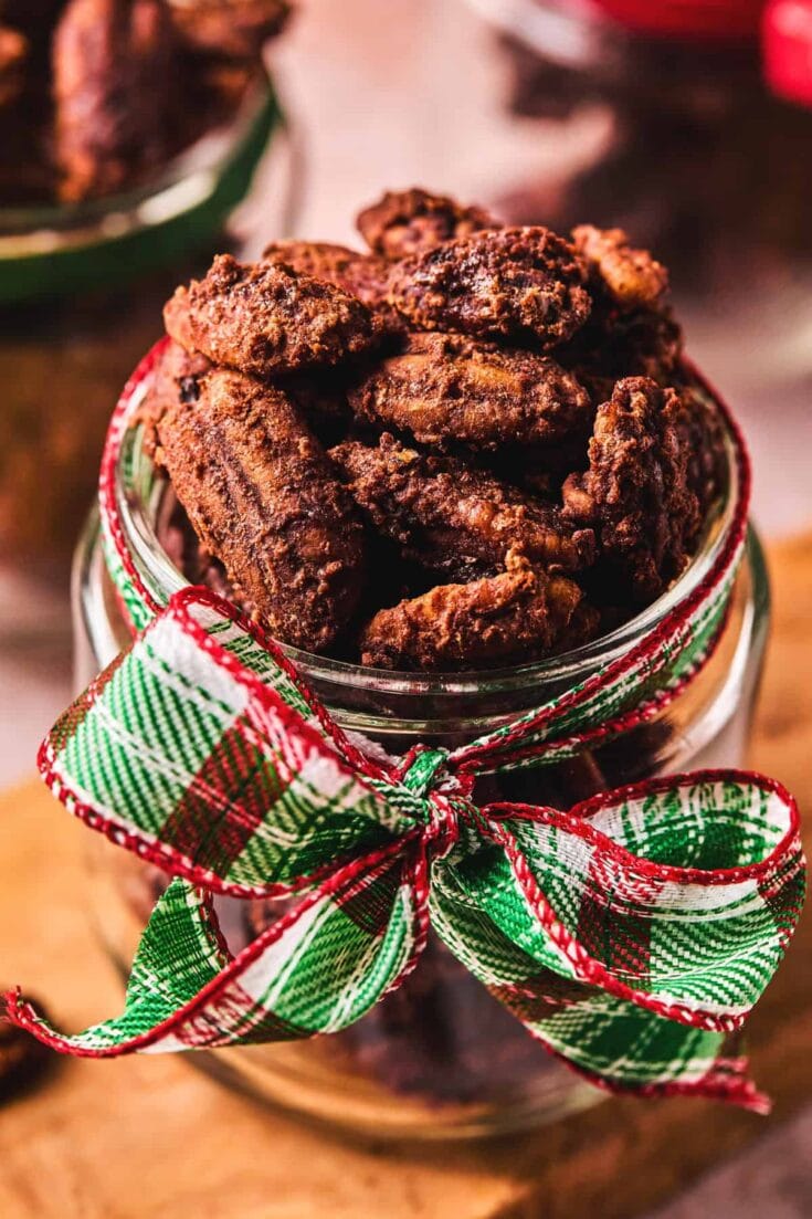 Jar of chocolate clusters with a festive red-green plaid ribbon, close-up shot highlighting crunchy cocoa-dusted treats in a glass jar.